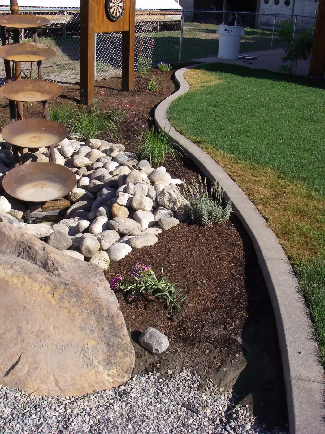 Curved concrete landscape curbing surrounding a rock garden in a Logan, Utah backyard