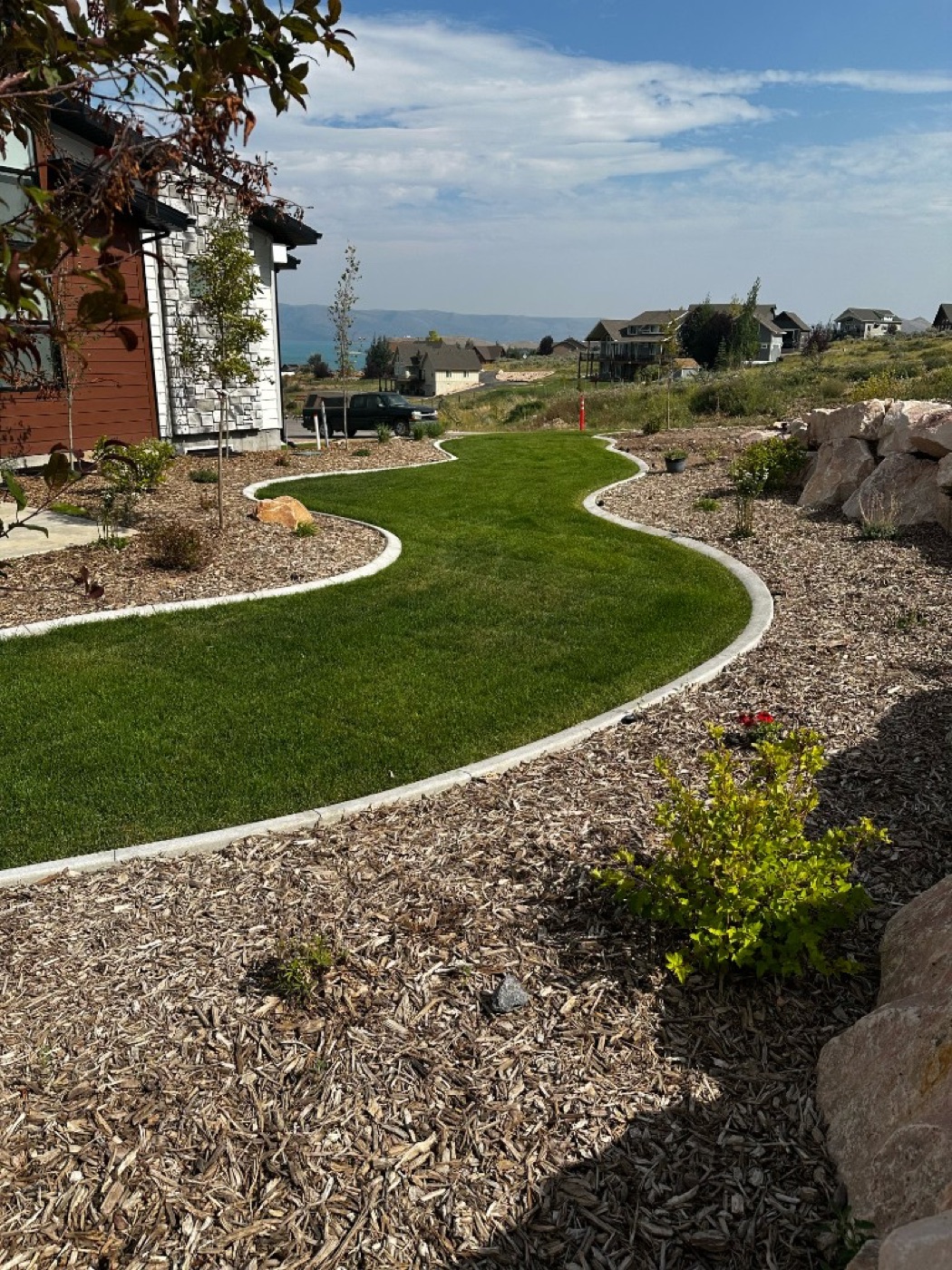 Winding S-curve concrete curbing separating lawn from mulch beds with Utah lake views